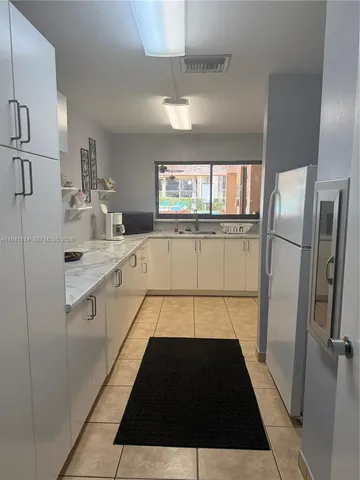 a large white kitchen with a sink and refrigerator