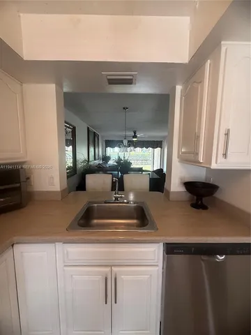 a view of living room with granite countertop white cabinets and a potted plant