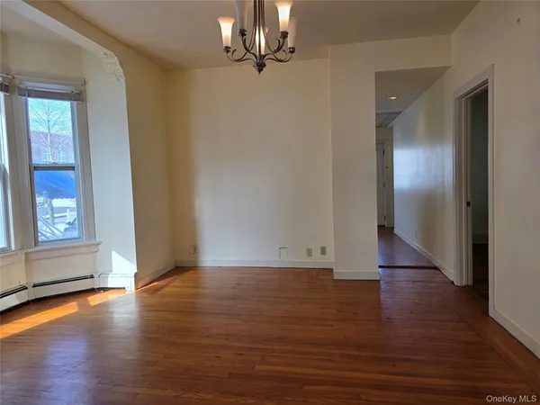 an empty room with wooden floor mirror and windows