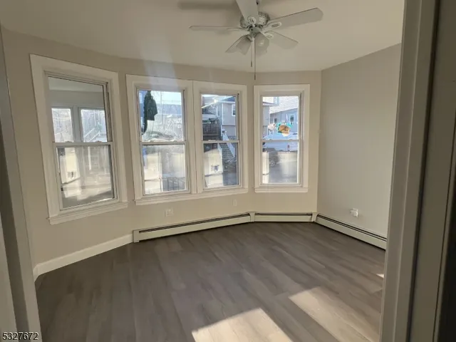 an empty room with wooden floor fan and windows