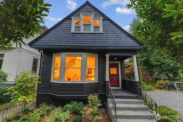 a view of a house with a small yard plants and large tree