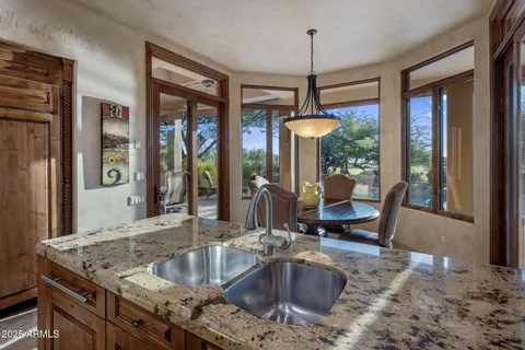 a kitchen view with granite countertop a sink and a large window