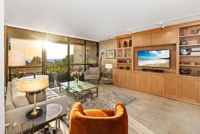 a living room with furniture a flat screen tv and a floor to ceiling window
