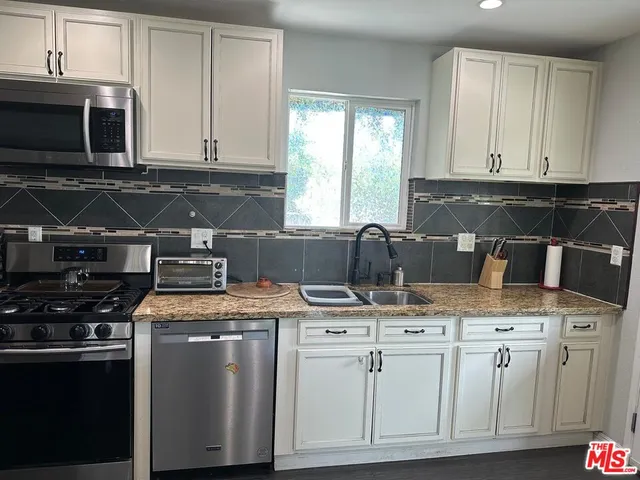 a kitchen with granite countertop a stove sink and cabinets