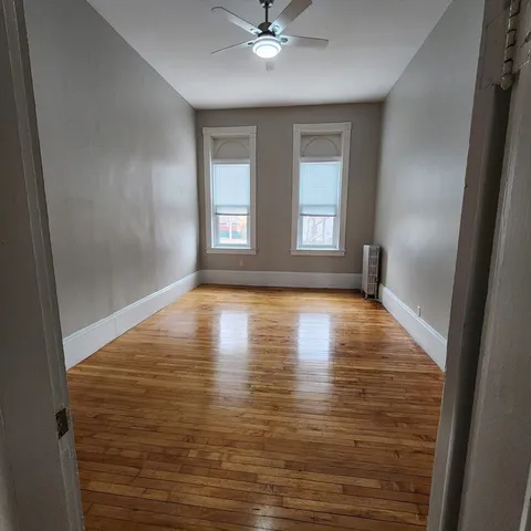 a view of empty room with wooden floor and fan