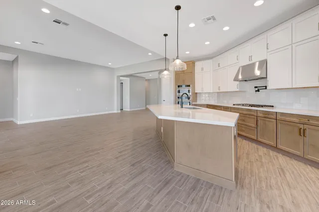 a large kitchen with kitchen island a sink and a stove in it