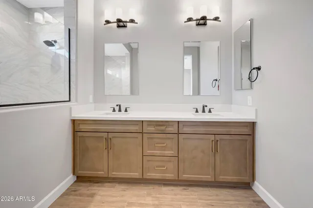 a spacious bathroom with a double vanity sink a mirror and a shower