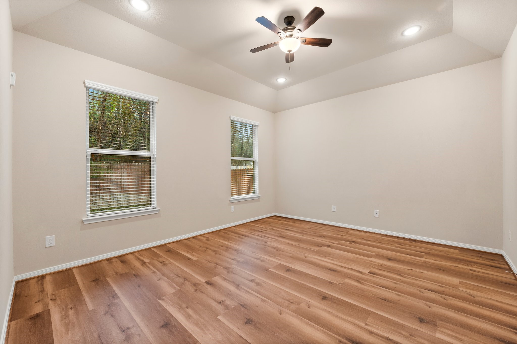 22314 Forbes Field Trail Spring, TX 77389 - Photo 18 of 46 The primary bedroom is spacious and offers fantastic back yard greenbelt views, new wood flooring in 2025, a tray ceiling, recessed lighting, and ceiling fan with light.