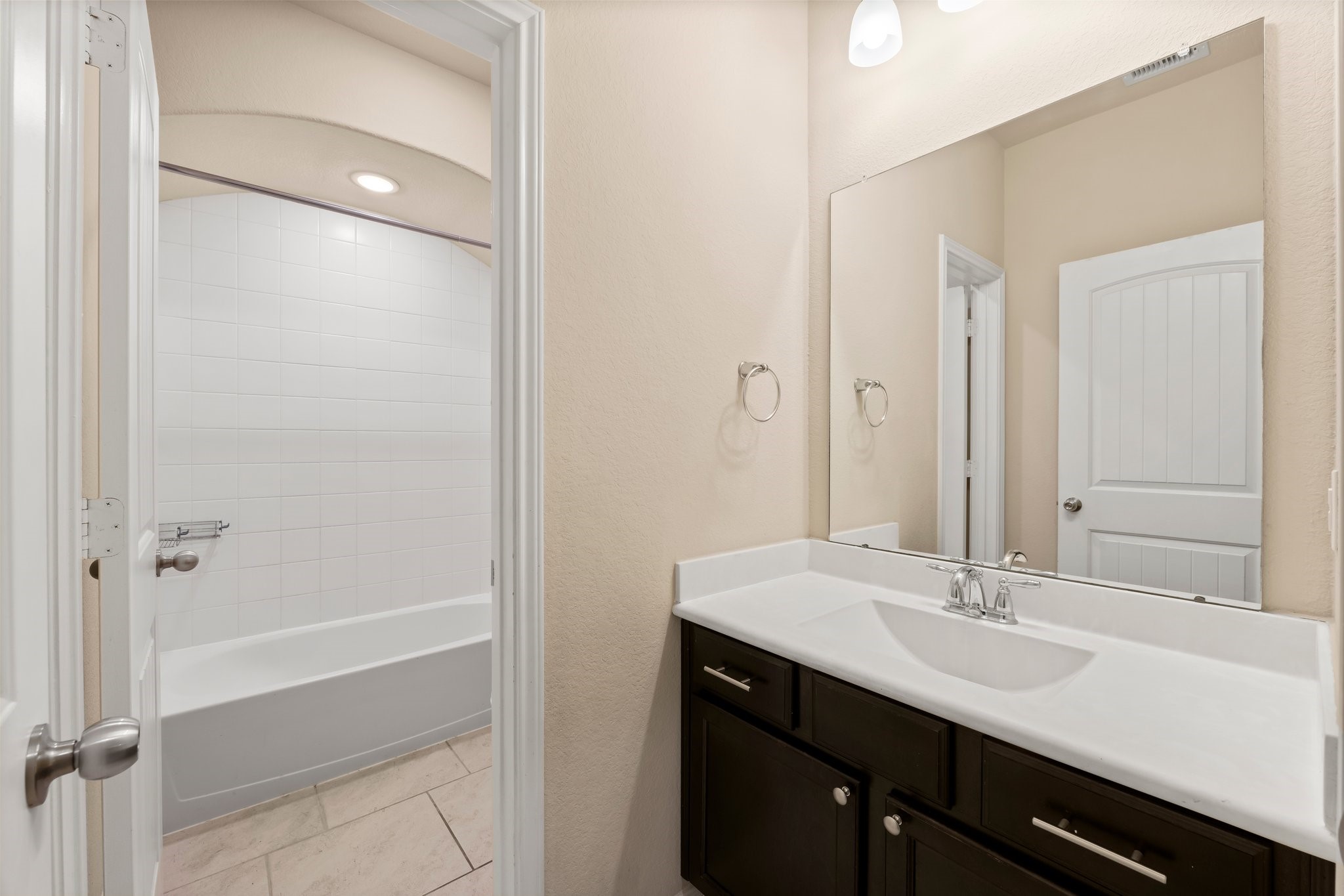 22314 Forbes Field Trail Spring, TX 77389 - Photo 30 of 46 Secondary bath includes single sink with solid surface counter top and integrated bowl, tile flooring, and separate area which includes commode and tiled shower/tub combo with rain head, arched ceiling, and toiletry cubby.
