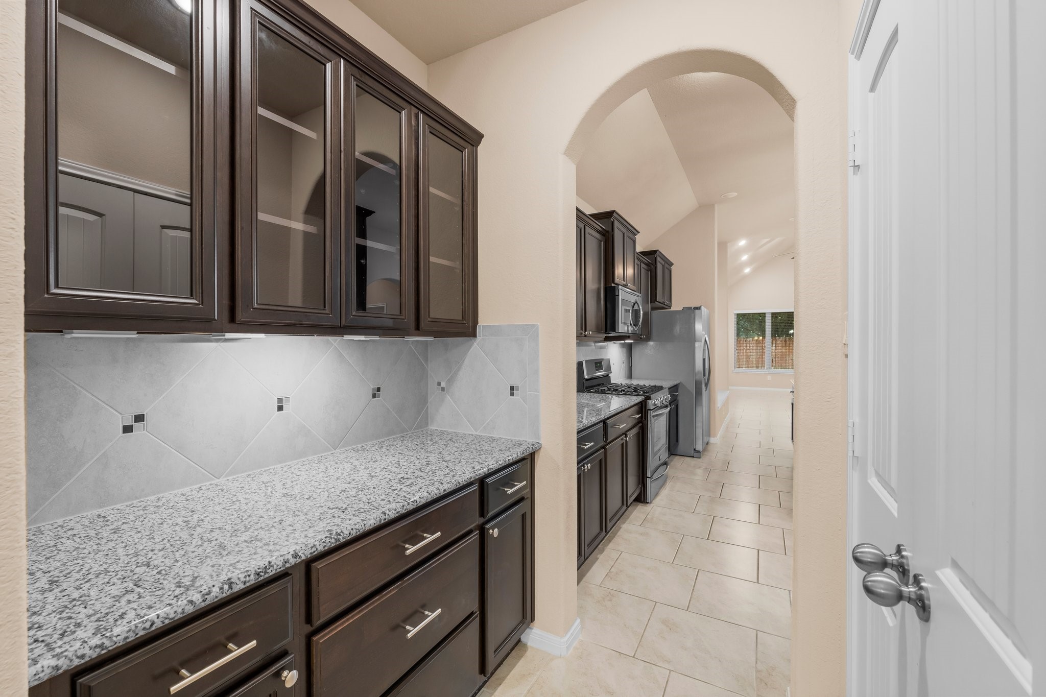22314 Forbes Field Trail Spring, TX 77389 - Photo 7 of 46 Butler's pantry between Dining and Kitchen includes granite counter tops, diagonal tile back splash, undercabinet lighting, and glass front cabinets. There is also a large walk-in pantry to the right as well!