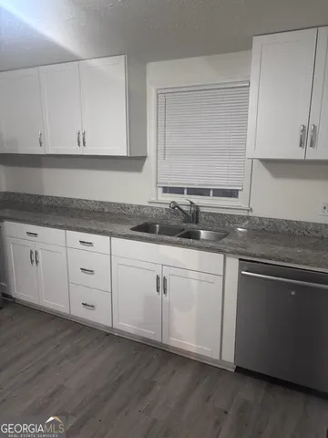 a kitchen with granite countertop white cabinets white appliances and a sink