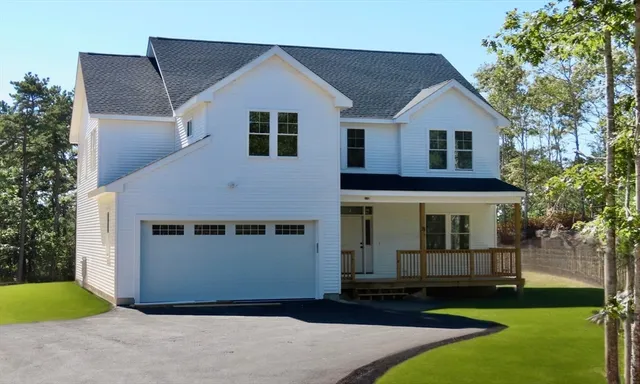 a front view of a house with a yard and trees