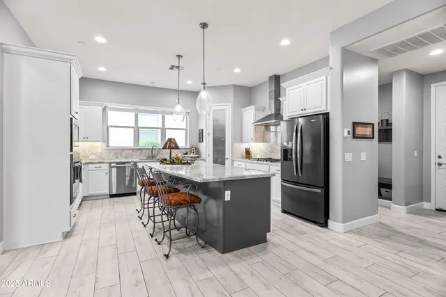 a kitchen with stainless steel appliances kitchen island granite countertop a refrigerator a sink a stove and a wooden floors