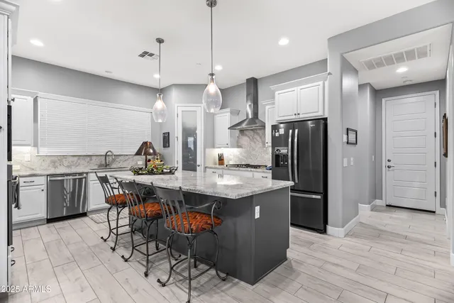 a kitchen with stainless steel appliances kitchen island granite countertop a table chairs and a refrigerator