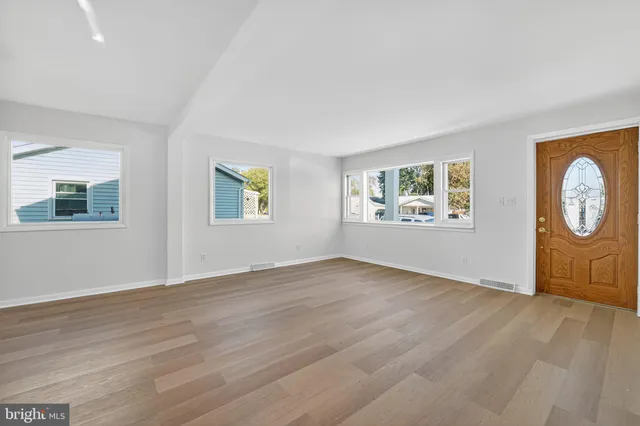 a view of an empty room with a window and wooden floor