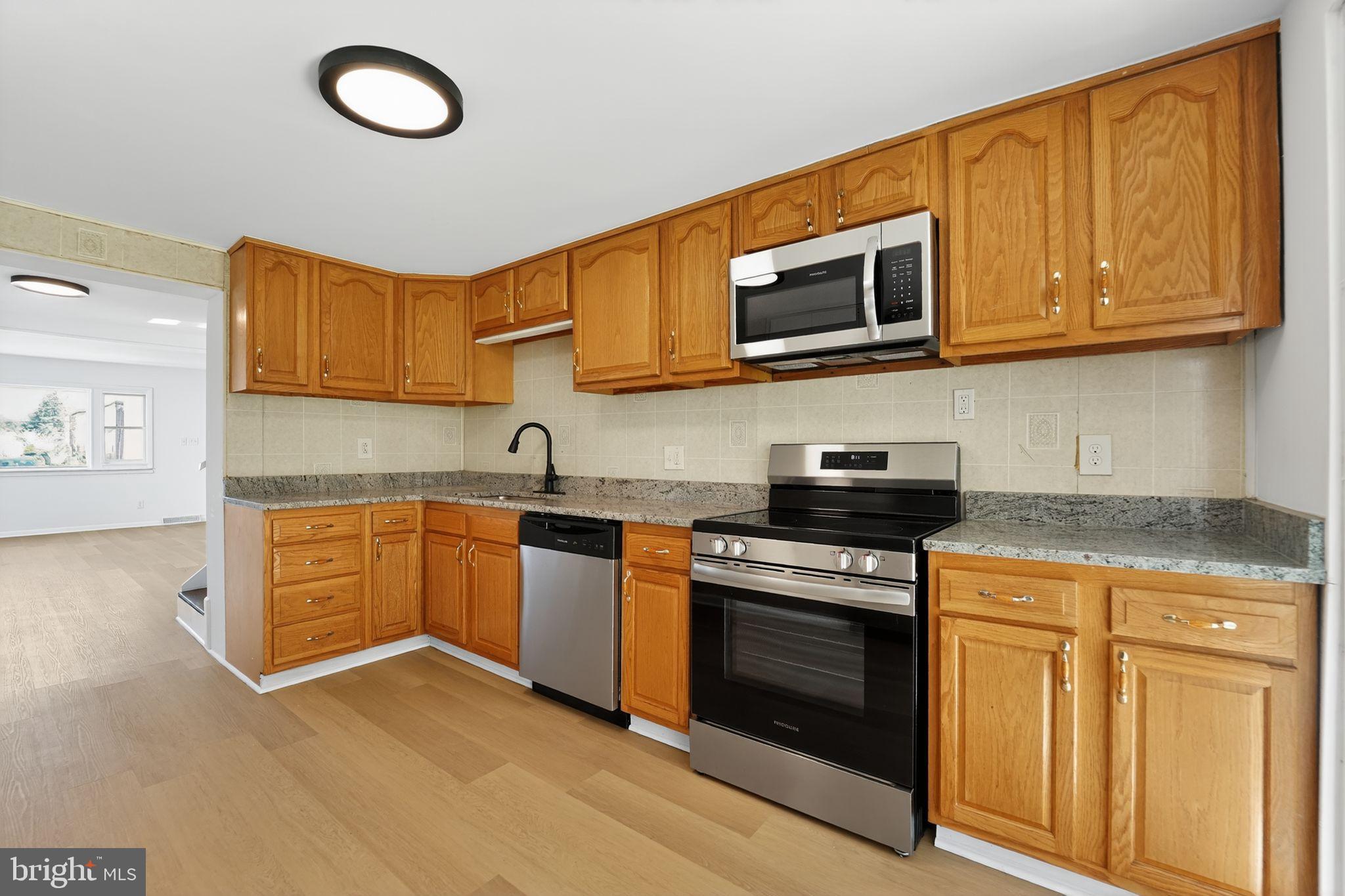 1008 Fuselage Avenue Baltimore, MD 21220 - Photo 10 of 30 a kitchen with stainless steel appliances granite countertop a stove top oven microwave and sink