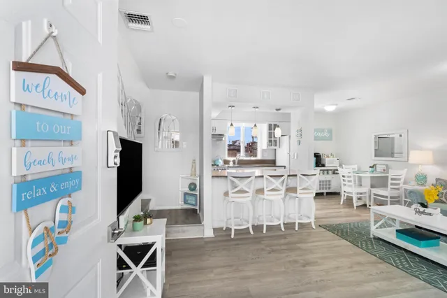 a living room with stainless steel appliances furniture a rug and a kitchen view
