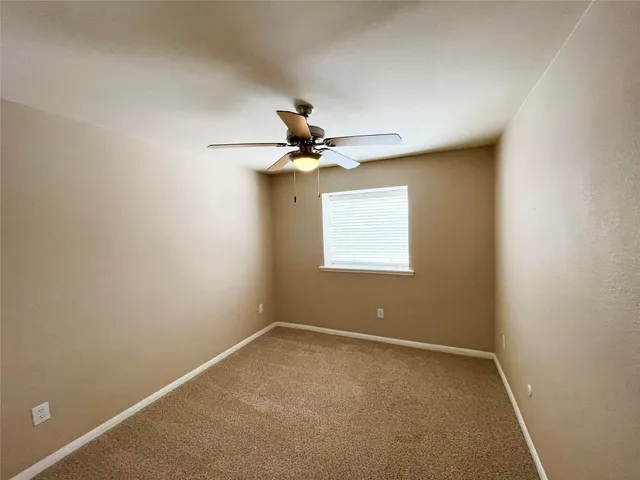 an empty room with a ceiling fan and a window