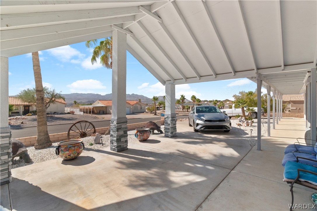 784 Pegasus Ranch Road Bullhead City, AZ 86429 - Photo 65 of 100 Covered carport with concrete flooring, stone-clad support pillars, and an extended covered walkway