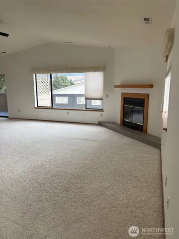 an empty room with windows and fireplace