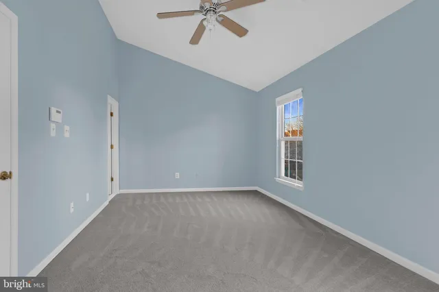 an empty room with a ceiling fan and window