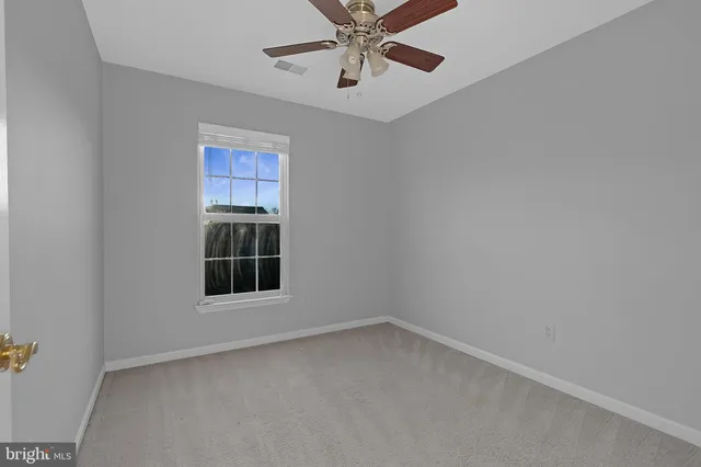 an empty room with a window and a ceiling fan