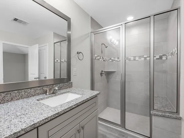 a bathroom with a granite countertop sink shower and a mirror