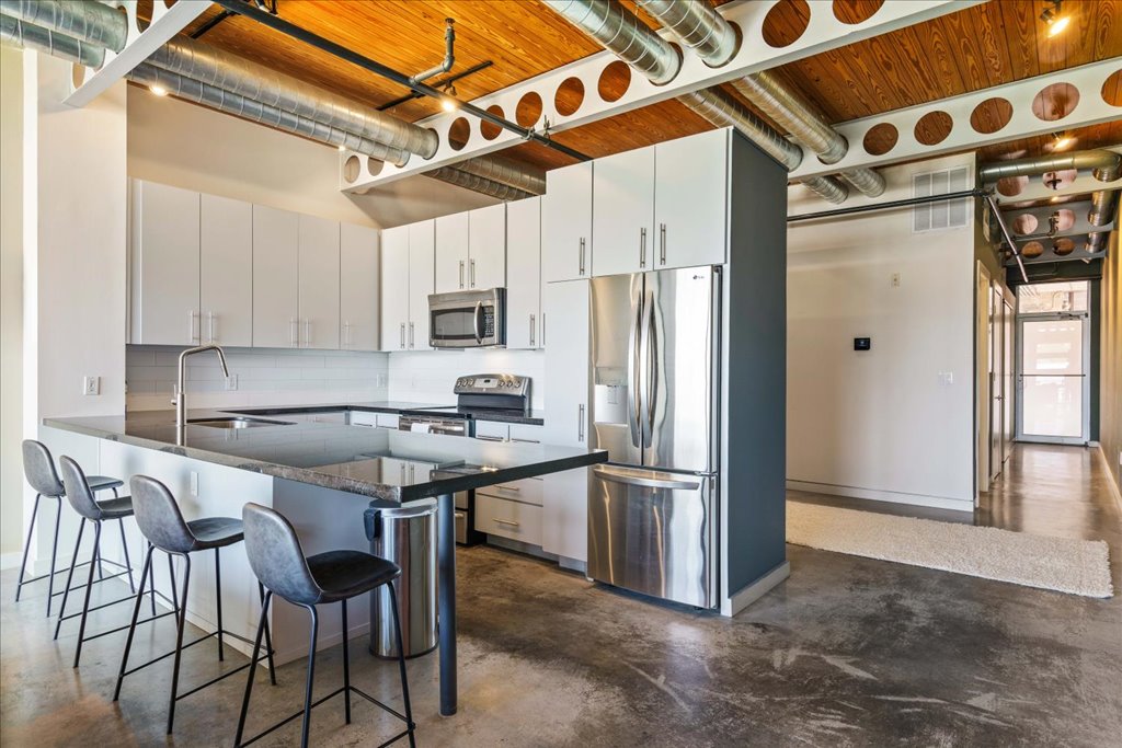1401 Eva Street, Unit 302 Austin, TX 78704 - Photo 5 of 15 Kitchen with stainless steel appliances, a kitchen bar, finished concrete flooring, a peninsula, and white cabinets