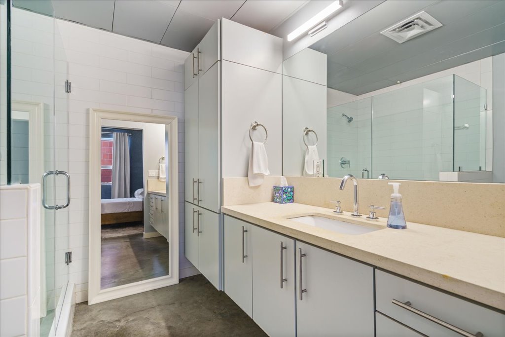 1401 Eva Street, Unit 302 Austin, TX 78704 - Photo 9 of 15 Ensuite bathroom with vanity, a shower stall, tile walls, and concrete flooring