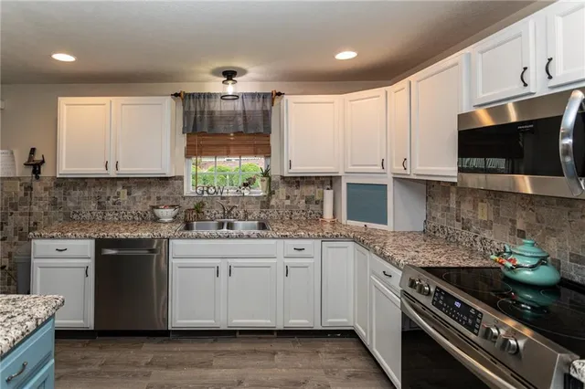 a kitchen with a sink a counter top space stainless steel appliances and a large window