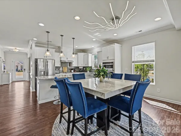 a view of a dining room and livingroom with furniture wooden floor a chandelier