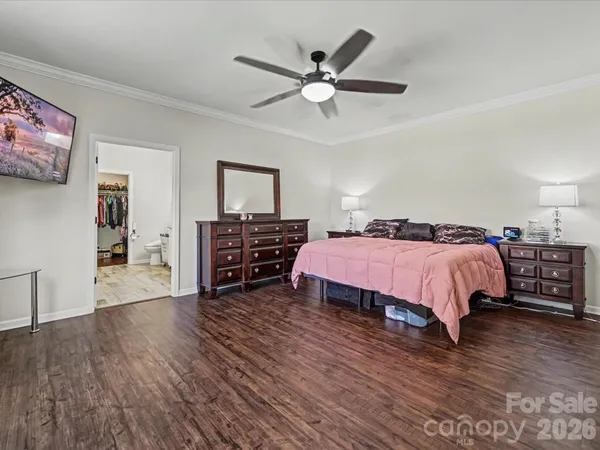 a spacious bedroom with a bed a dresser and a chandelier