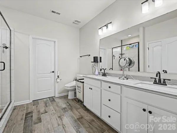 a spacious bathroom with a double vanity sink a toilet and a mirror