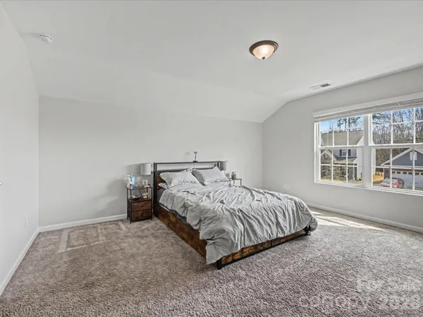 a bed sitting in a spacious bedroom next to a window