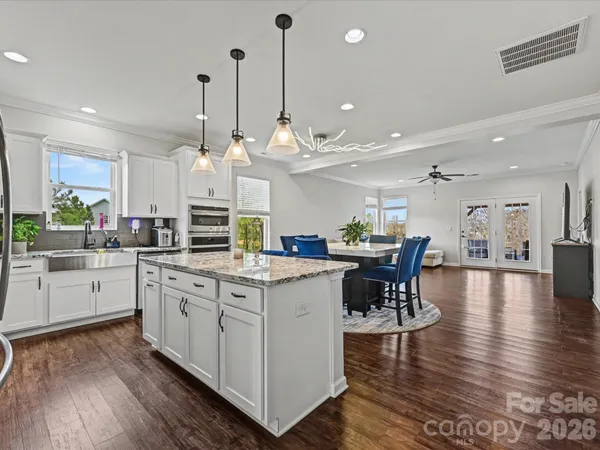 a kitchen with stainless steel appliances kitchen island granite countertop a table chairs and a chandelier