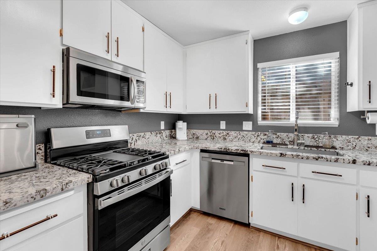 2110 Gentry Way Red Bluff, CA 96080 - Photo 11 of 47 a kitchen with stainless steel appliances granite countertop white cabinets a sink a stove a microwave and wooden floors