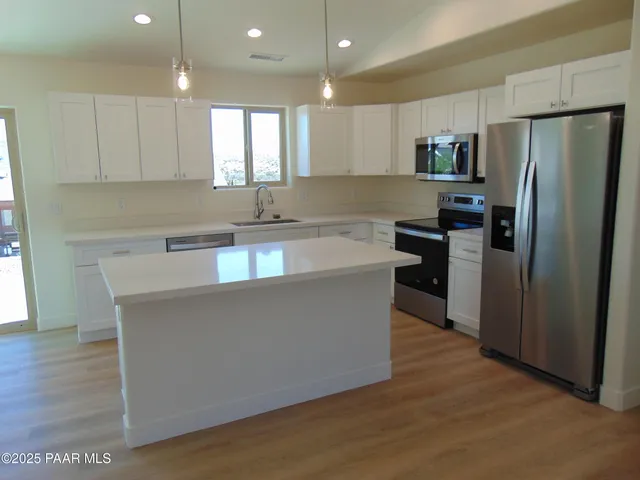 a kitchen with stainless steel appliances granite countertop a refrigerator a sink a stove a microwave and wooden floor