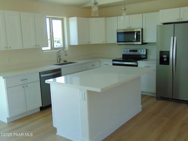 a kitchen with stainless steel appliances a refrigerator a sink a stove a microwave and wooden floors