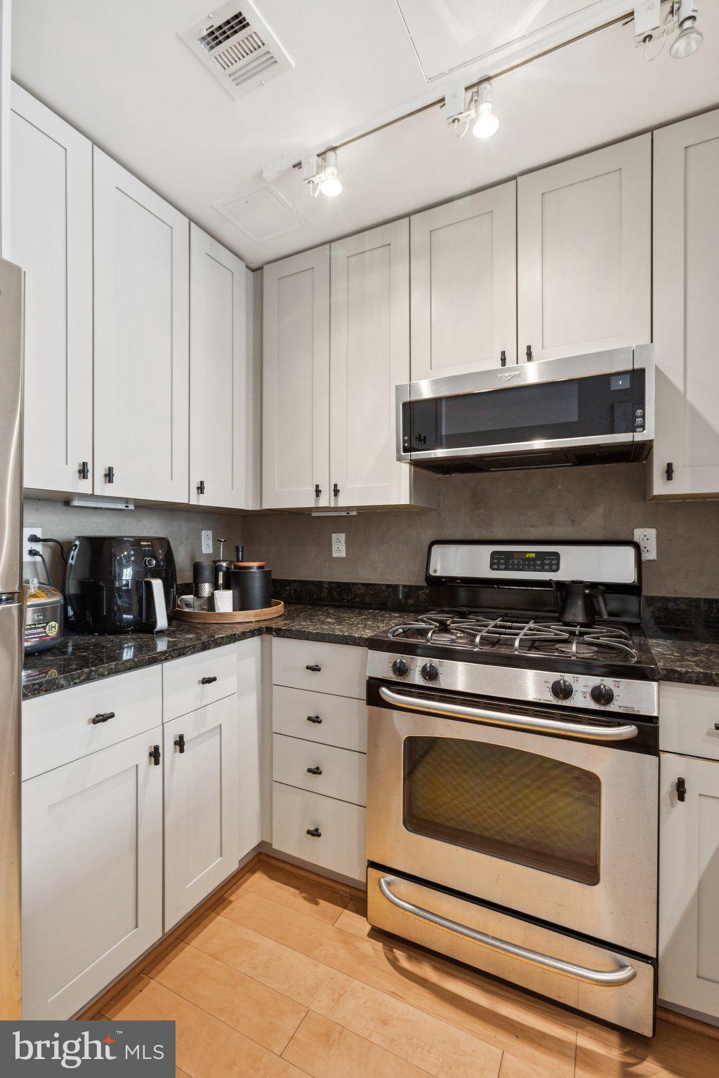 301 Massachusetts Avenue Northwest, Unit 606 Washington, DC 20001 - Photo 6 of 25 a kitchen with stainless steel appliances granite countertop a stove a sink and white cabinets
