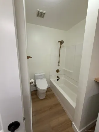 a bathroom with a bathtub shower sink vanity and toilet