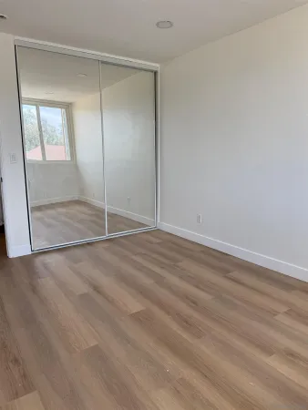 an empty room with wooden floor and mirror
