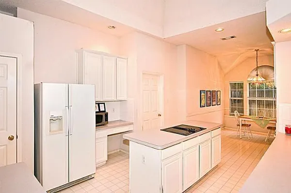 a kitchen that has a refrigerator a stove and white cabinets with wooden floor
