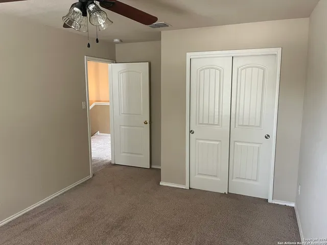 an empty room with chandelier fan and closet area