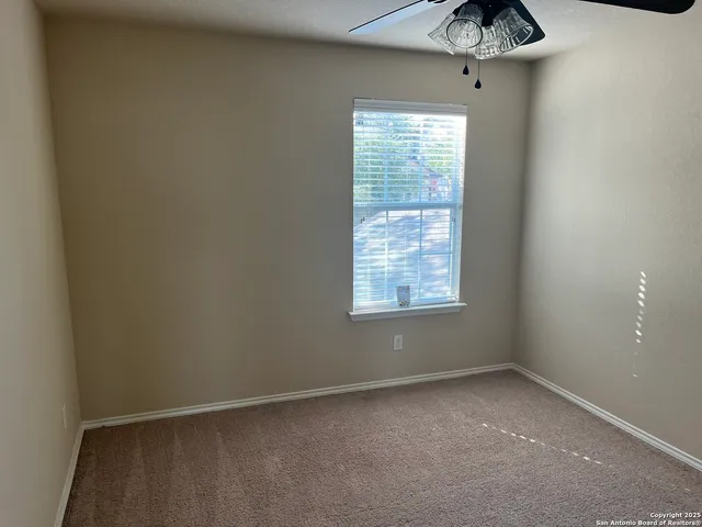 an empty room with a window and a fan