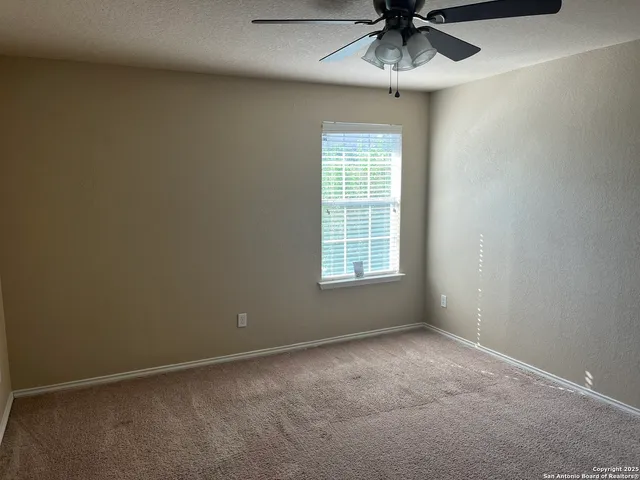 an empty room with a window and a fan