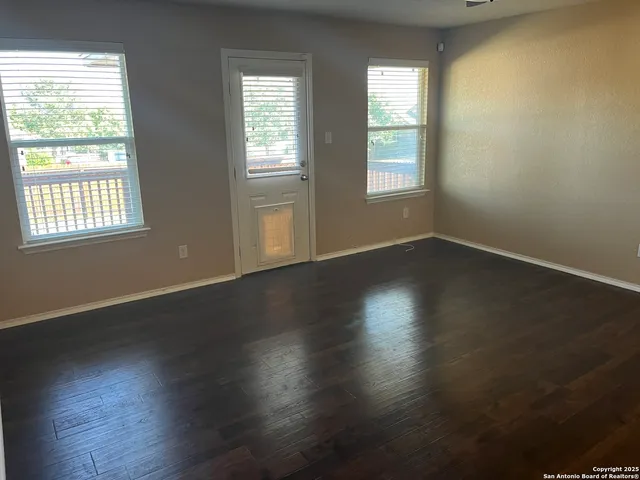 an empty room with wooden floor and windows