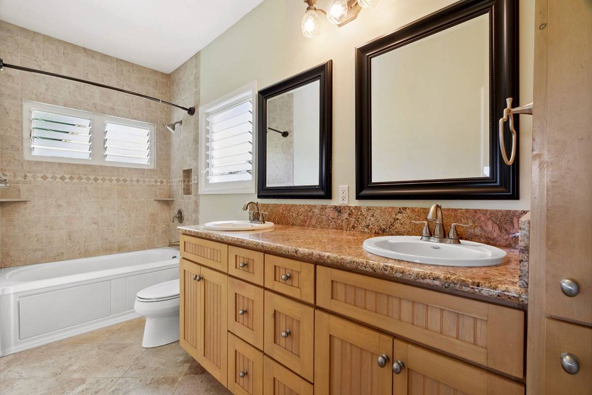 1661 Huli Road Kilauea, HI 96754 - Photo 23 of 28 a bathroom with a granite countertop toilet a sink a mirror and a bathtub