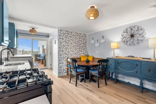 a kitchen with stainless steel appliances granite countertop a stove a sink a dining table and chairs with wooden floor