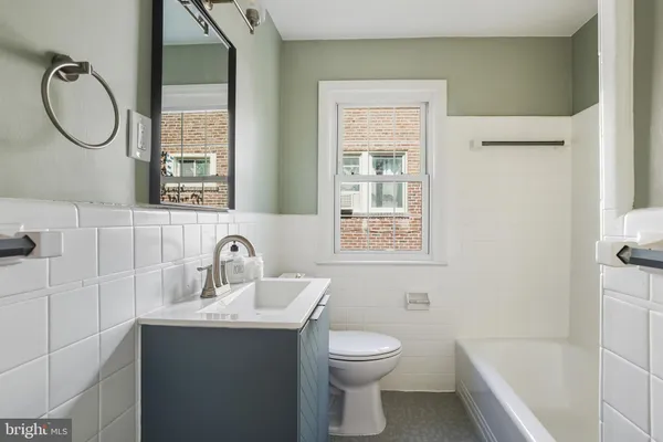 a bathroom with a toilet sink vanity tub and mirror