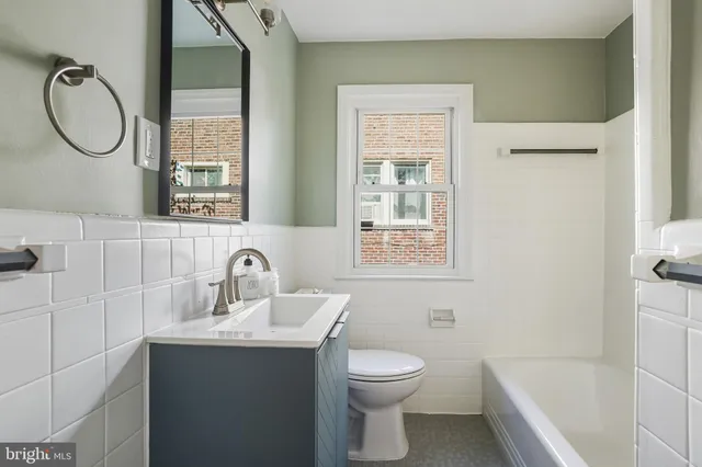 a bathroom with a toilet sink vanity tub and mirror